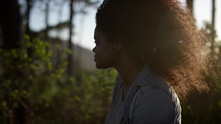 A woman with curly hair is standing in the wind