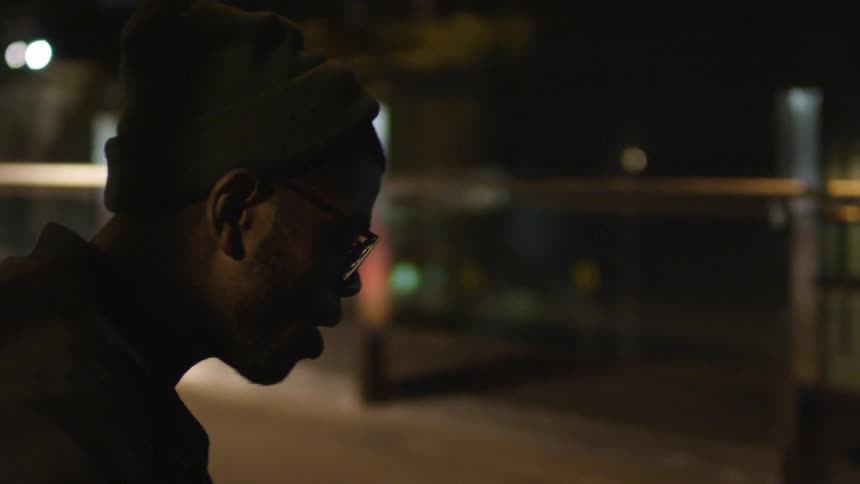 A man is sitting outside at night as he gets up and walks off