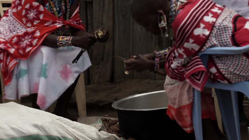 African women sitting and peeling potatoes with knives