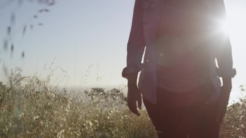 A woman walks through a field in the day time