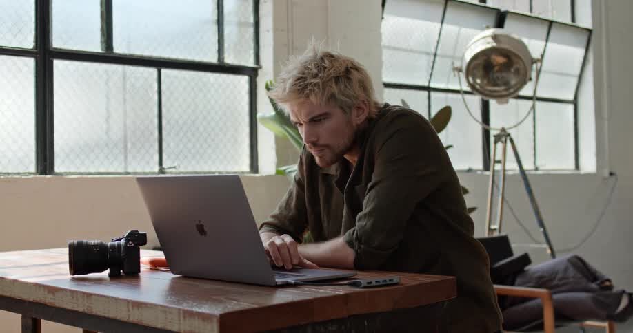 A man sits at a desk working on a laptop computer