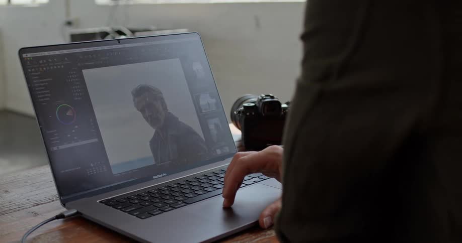 A person looking at a photo on a laptop next to a camera