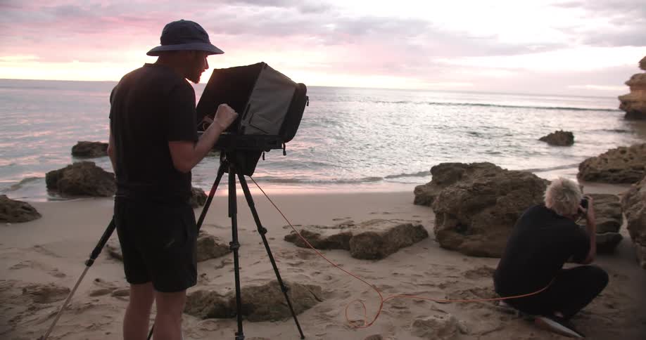 A photographer takes pictures of a man on a beach