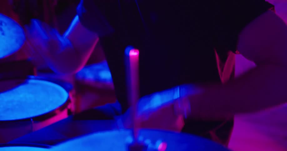 Drummer plays drums in uv illuminated studio