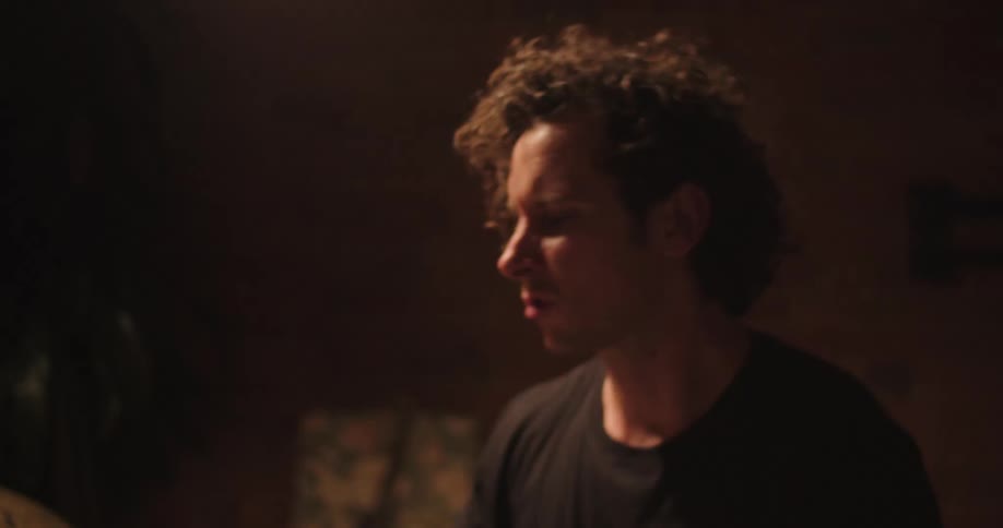 A man plays the drums in a room with dim lighting