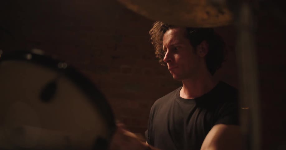 A man plays the drums on a dark stage