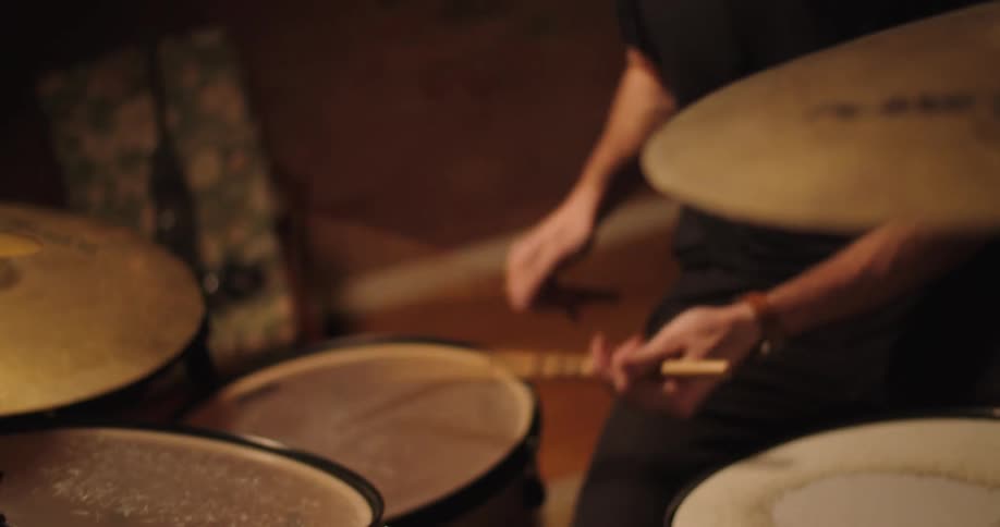 A man rapidly striking drums on a drum set