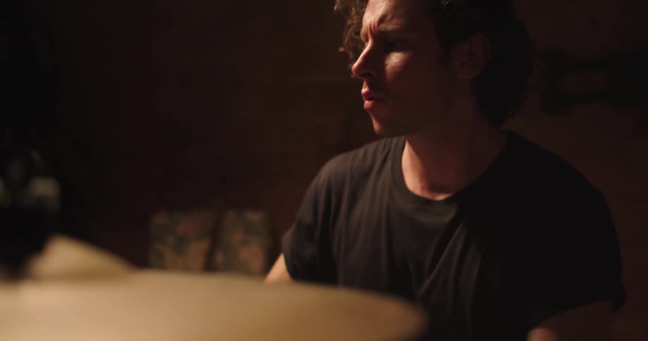 A musician skillfully plays the drums in a darkened room