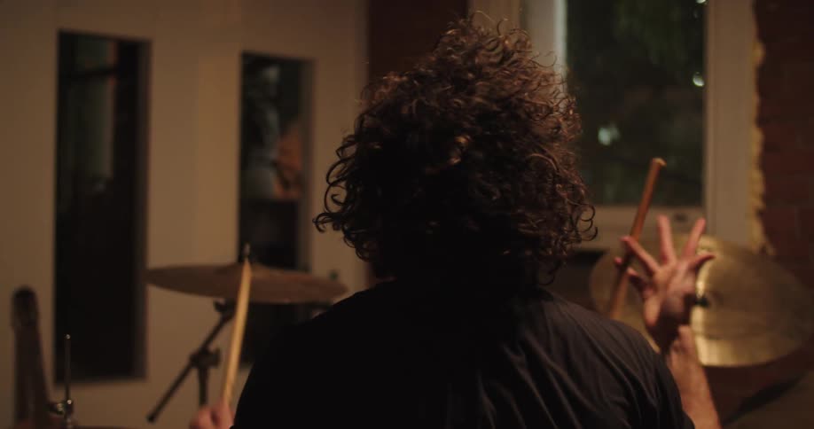 A man plays the drums and hangs his head in exhaustion
