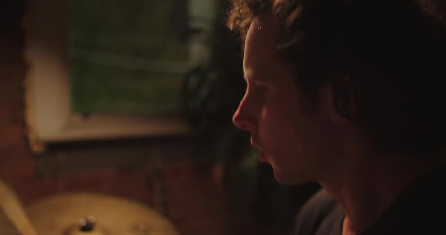 A young white man energetically plays the drums
