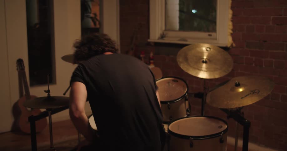 A drummer vigorously strikes his drums and cymbals before tossing his drumsticks in the air as he stands up and walks away from the drum set