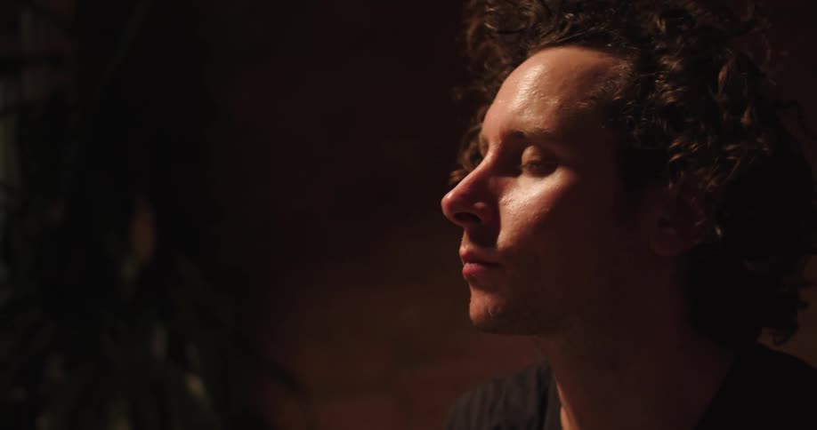A sweaty man breathes heavily and pushes his hair back from his face