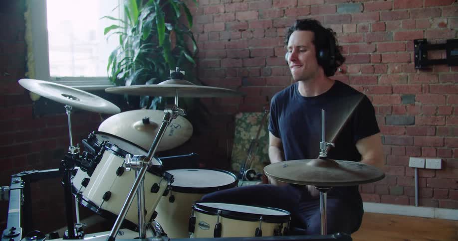 Drummer wearing headphones plays drums in the studio