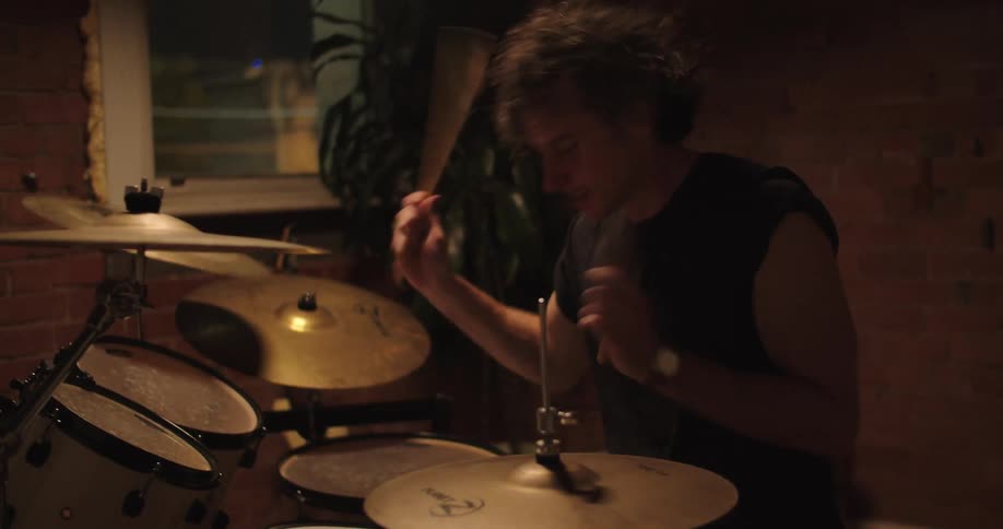 Musician plays drums on room indoors at night