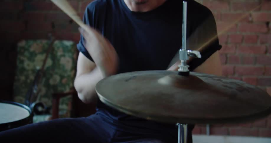 A man viciously uses his drum sticks to play the drums
