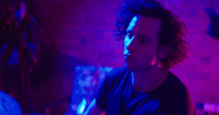 Drummer plays drums in the uv illuminated studio