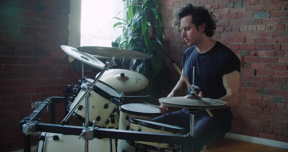 A drummer drumming on a drum set indoors