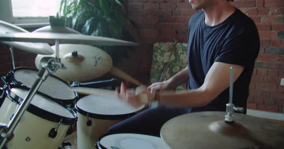 A man is playing drums by the window
