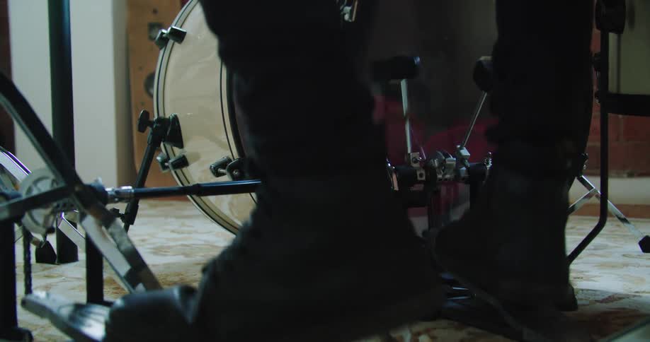 A drummer works the bass drum pedals on a drum kit