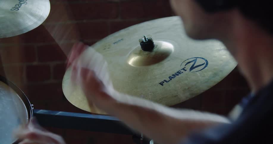 A drummer striking the cymbal of a drum set