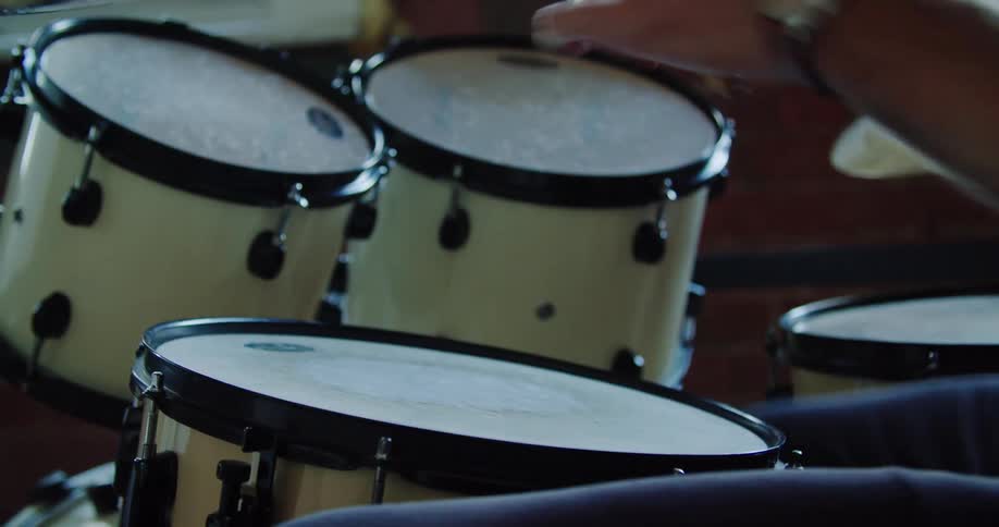 A person uses drumsticks on a set of drums