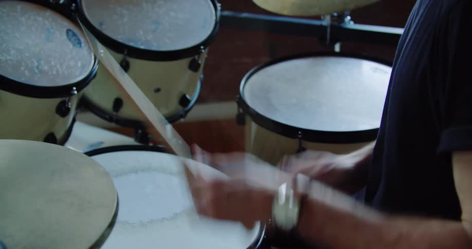 Drummer wearing headphones plays drums fast in the studio