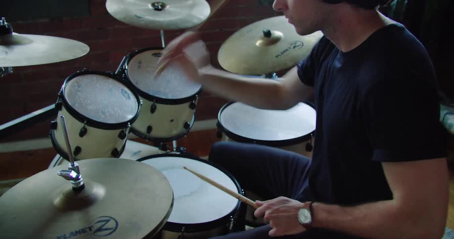 A man with headphones and drumsticks playing the drum