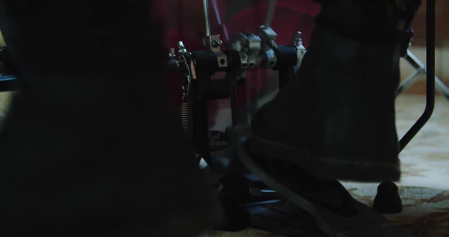 Drummer wearing low boots manipulates pedals