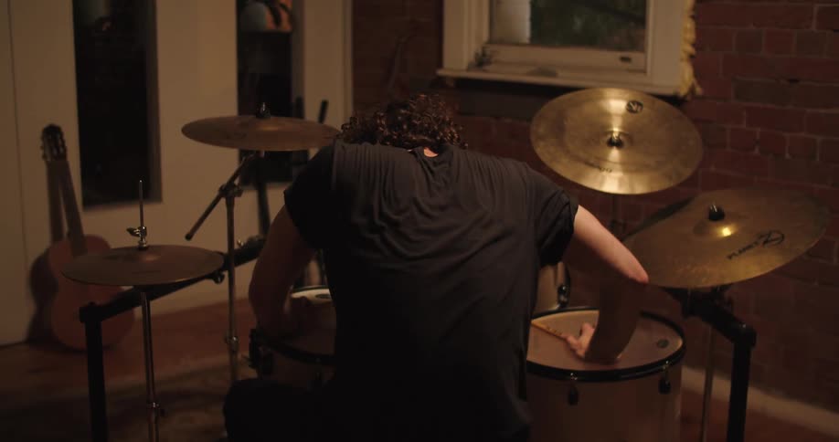 A drummer leans forward in exhaustion after playing