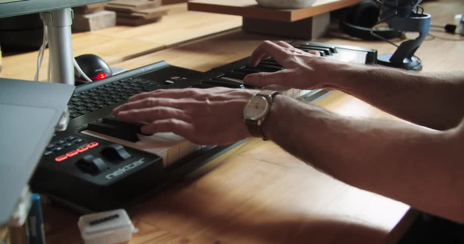 Musician playing on keyboard sitting at desk