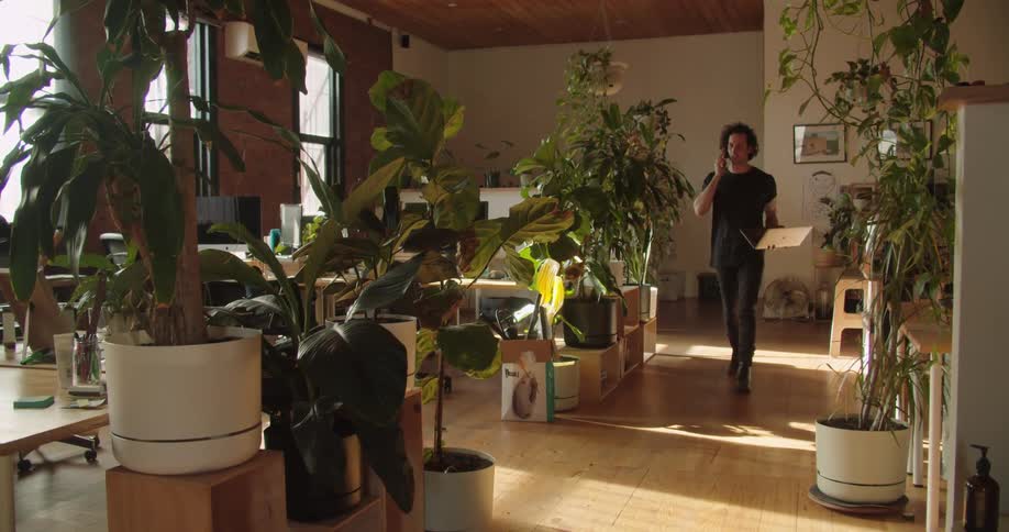 A man walks through the living room with a laptop and cell phone