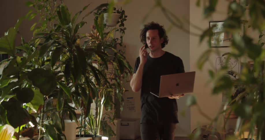 A man walks into his living room talking on the phone