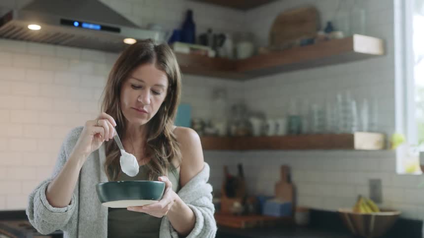 A woman standing in the kitchen eating