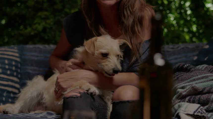 A woman caresses her dog on a couch
