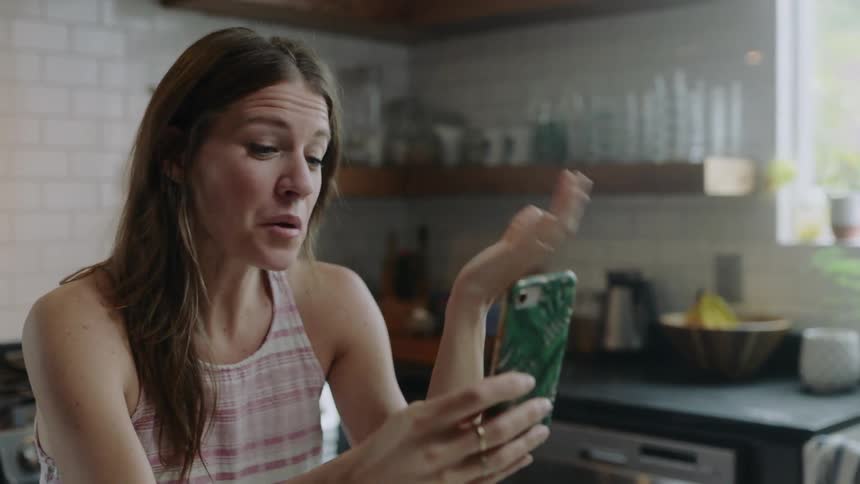 Woman smiles as she holds her cell phone and talks to it