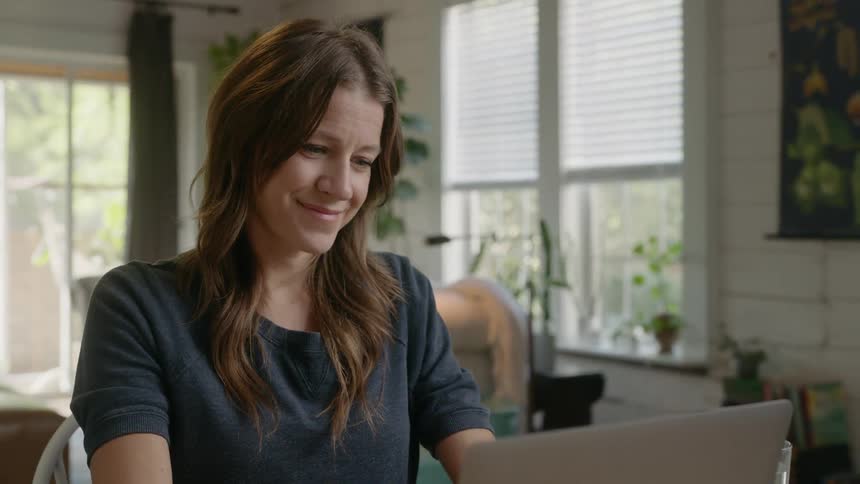 A woman sitting typing on a laptop