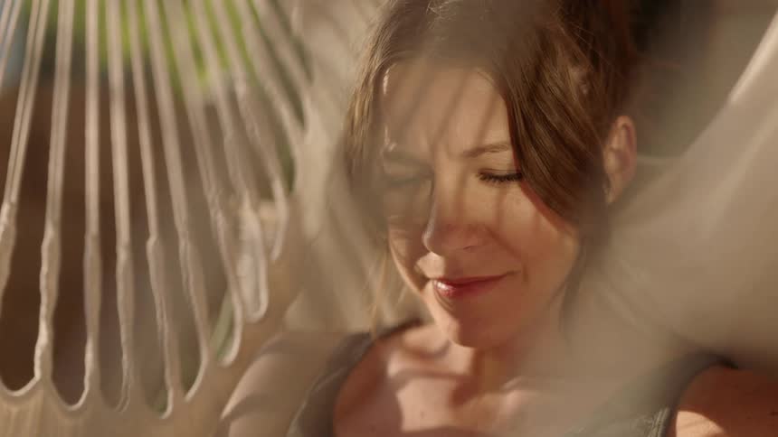 A young woman sits in a chair and smiles and thinks
