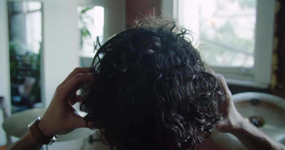 A man with curly hair places a set of earmuffs over his ears as he begins to play the drums