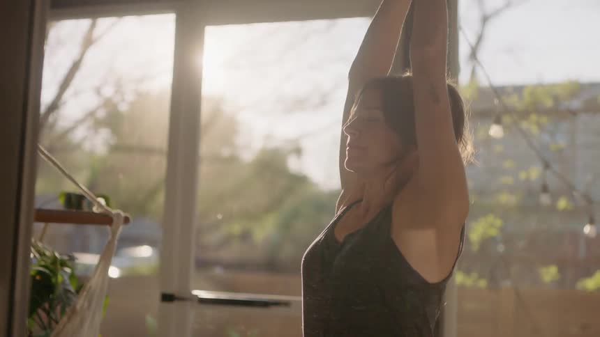 A woman stretches her arms in the air for yoga