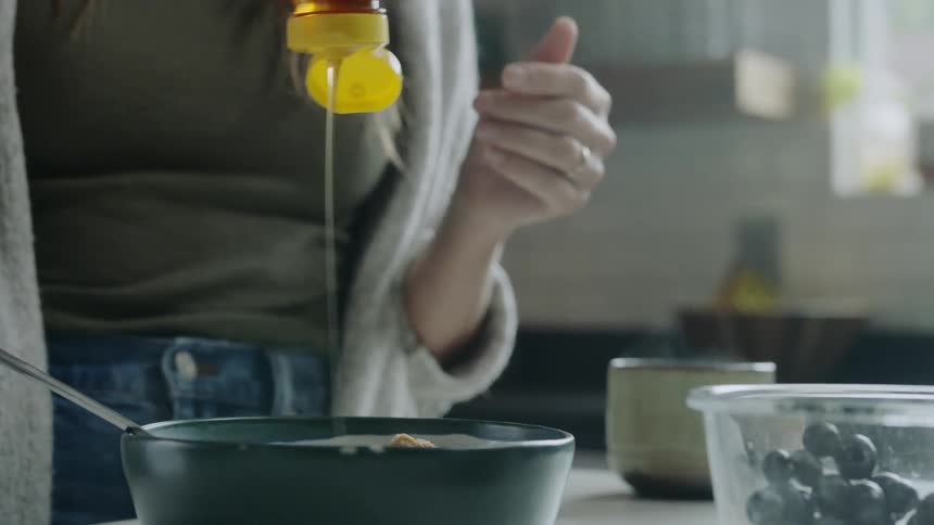 A white woman squirts honey into a metal pan
