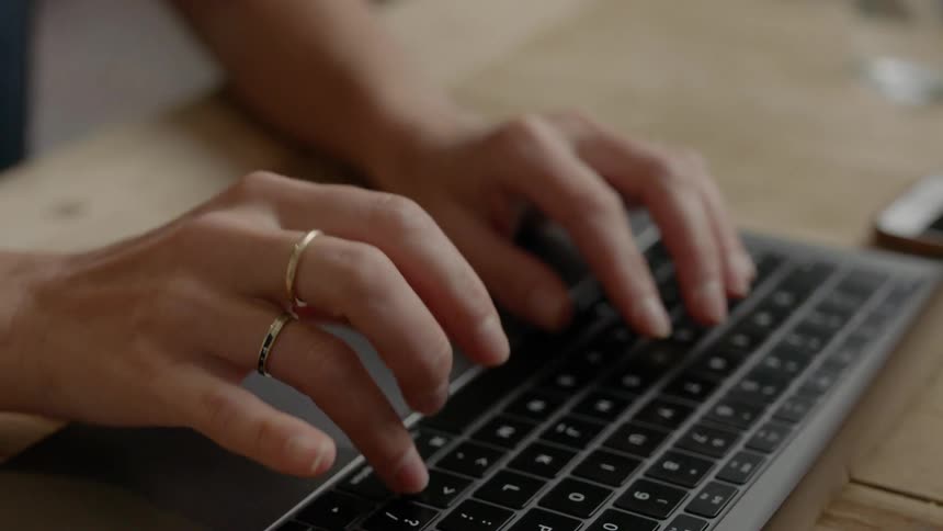 A woman sitting at a table typing on a laptop