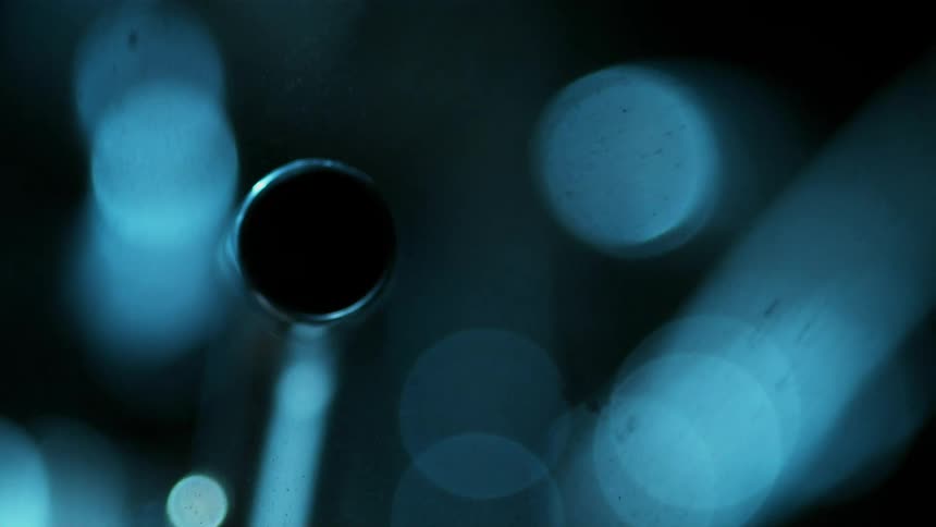 Pieces of small black debris float in the water as sparks emerge from a round object