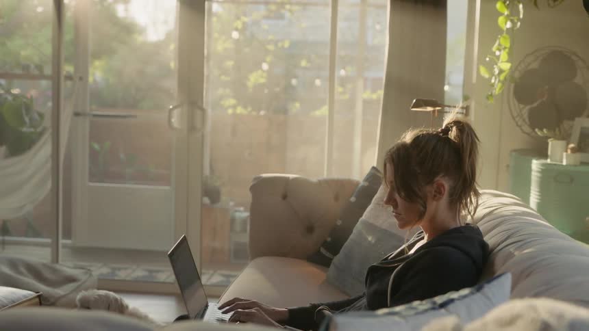 Woman sitting in couch working on laptop from home