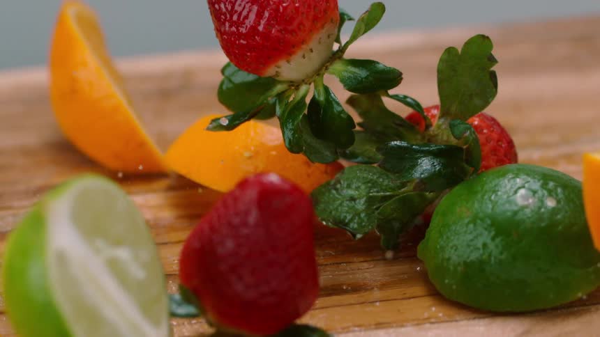 Several pieces of moist fruit are dropped onto a wooden cutting board