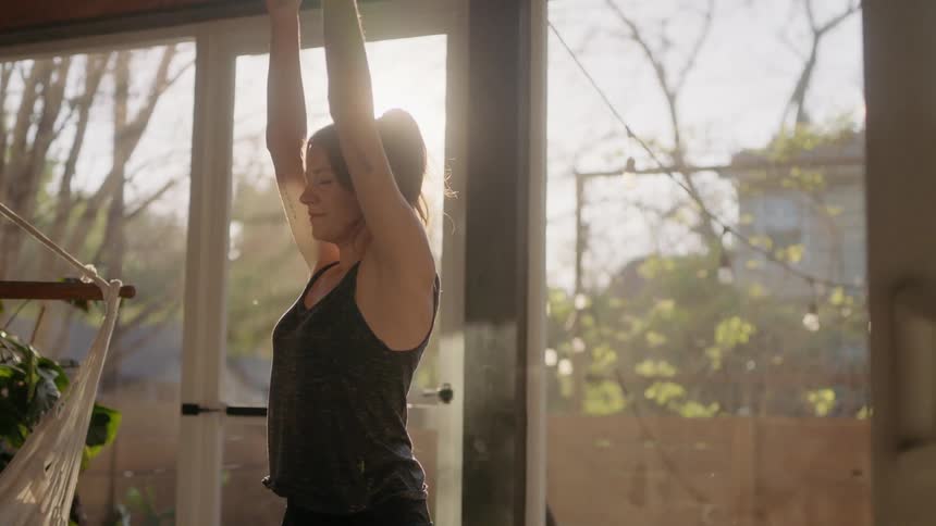 Middle aged woman practices yoga in the terrace of the house