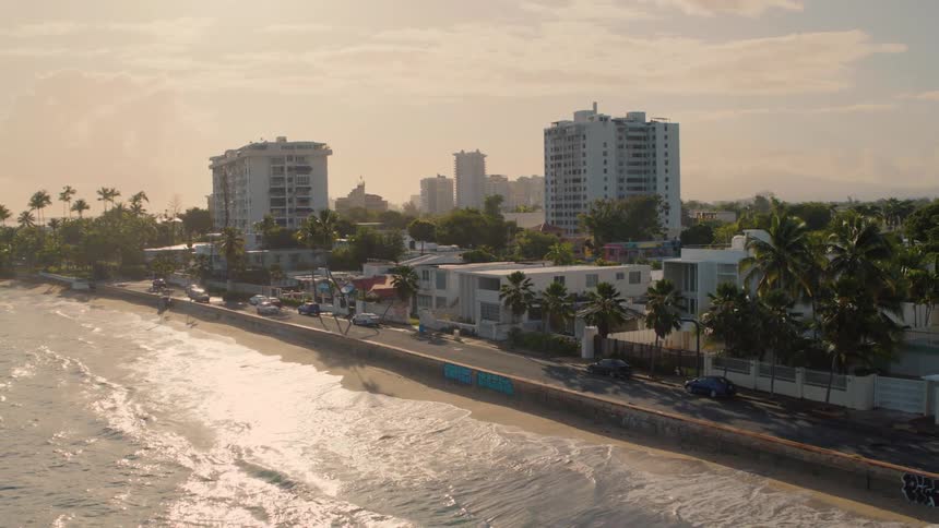 Waves crash onto the shore of a beach next to a city