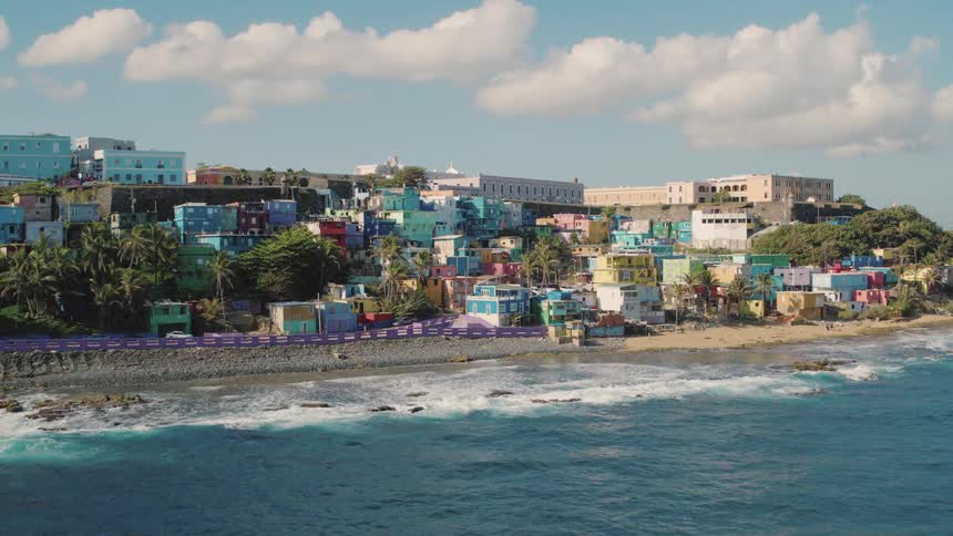 Waves crash on the shore near many colorful buildings