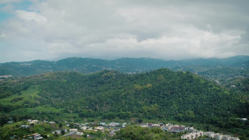 A neighborhood sits below hills covered with trees