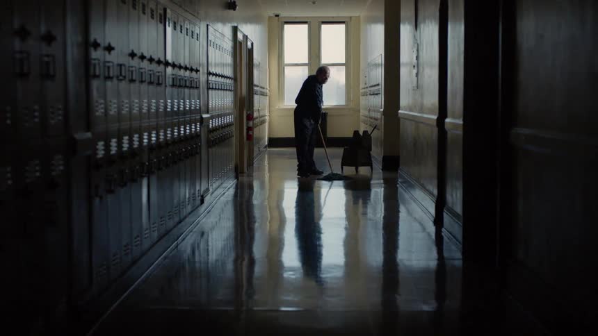 A janitor mops the floor in a school hallway