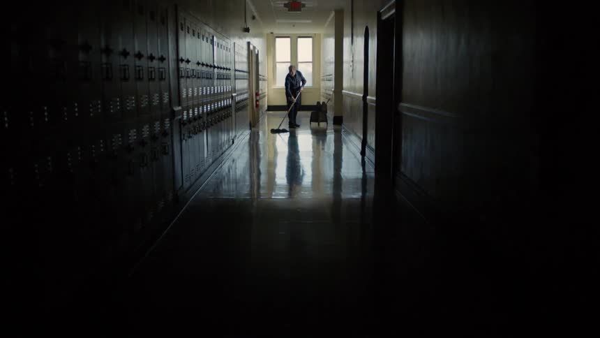 Caretaker mops the floor of the school corridor